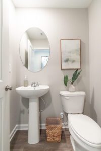 A bathroom with a decorative plant and painting.