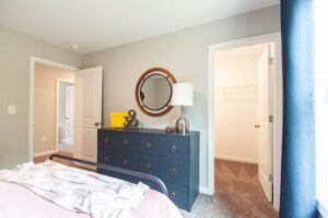 A room with a navy dresser showing a closet, hallway, and separate room.